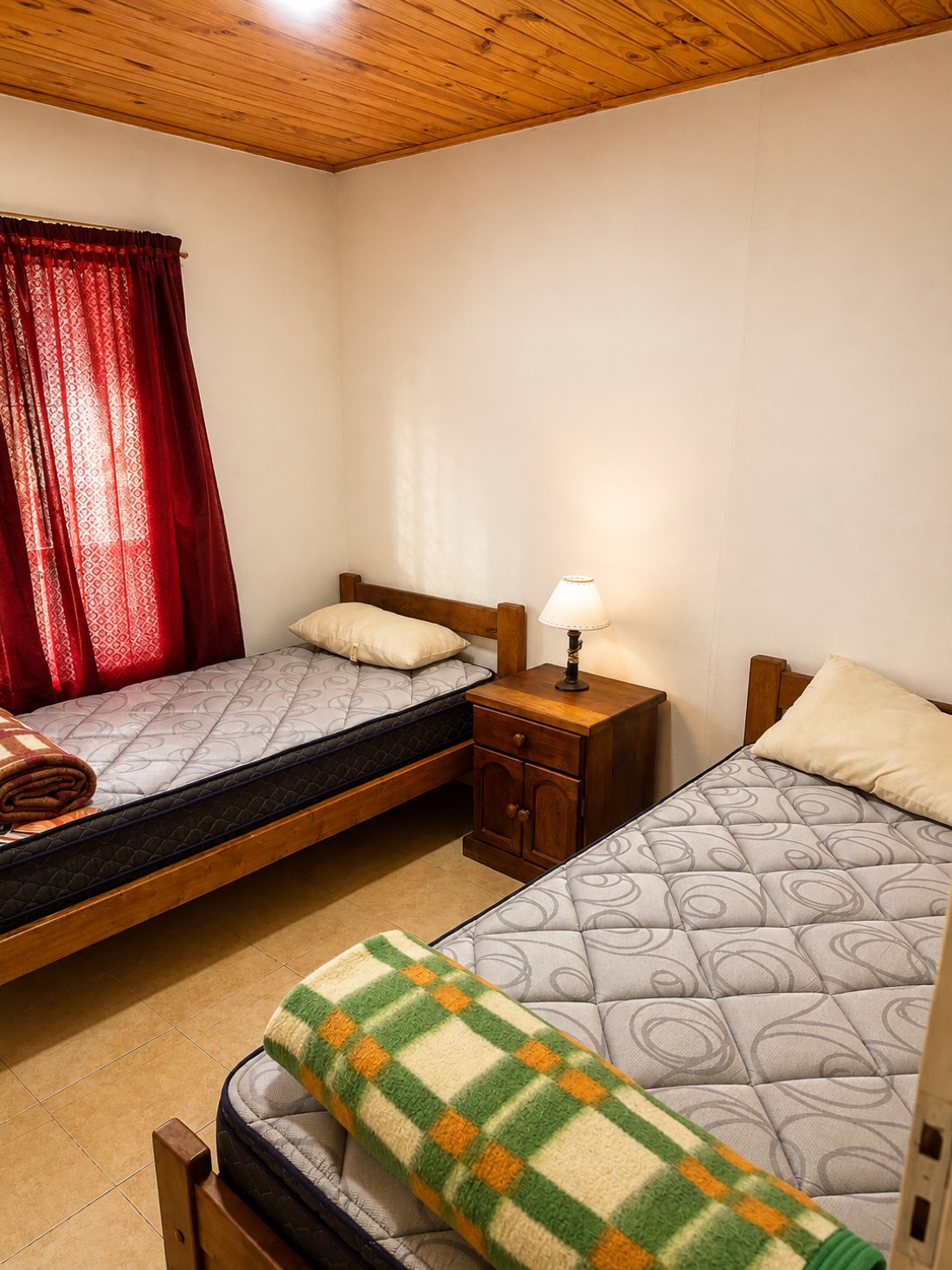 Dormitorio con dos camas individuales y cortinas rojas