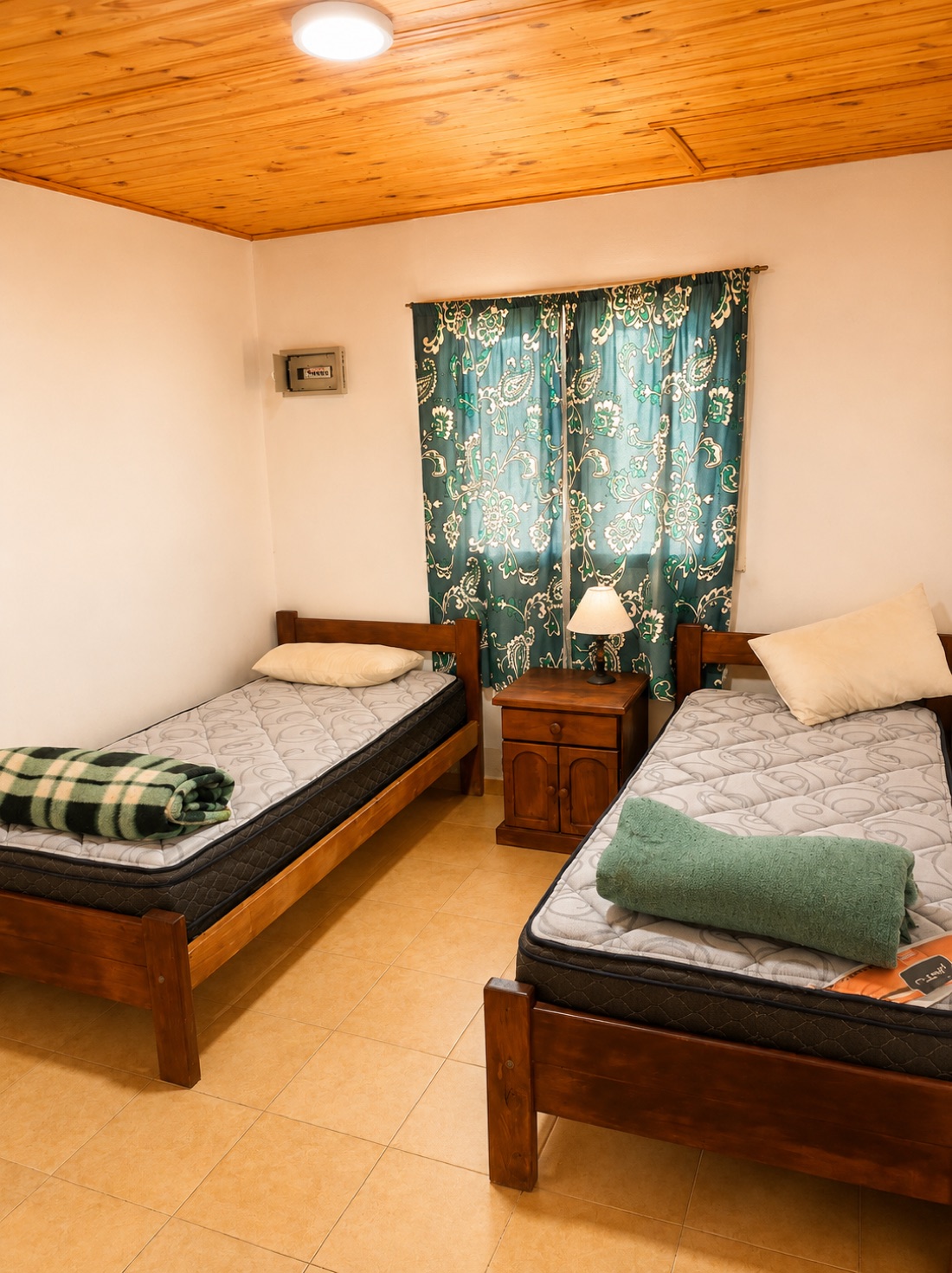 Dormitorio con dos camas individuales y cortinas verdes